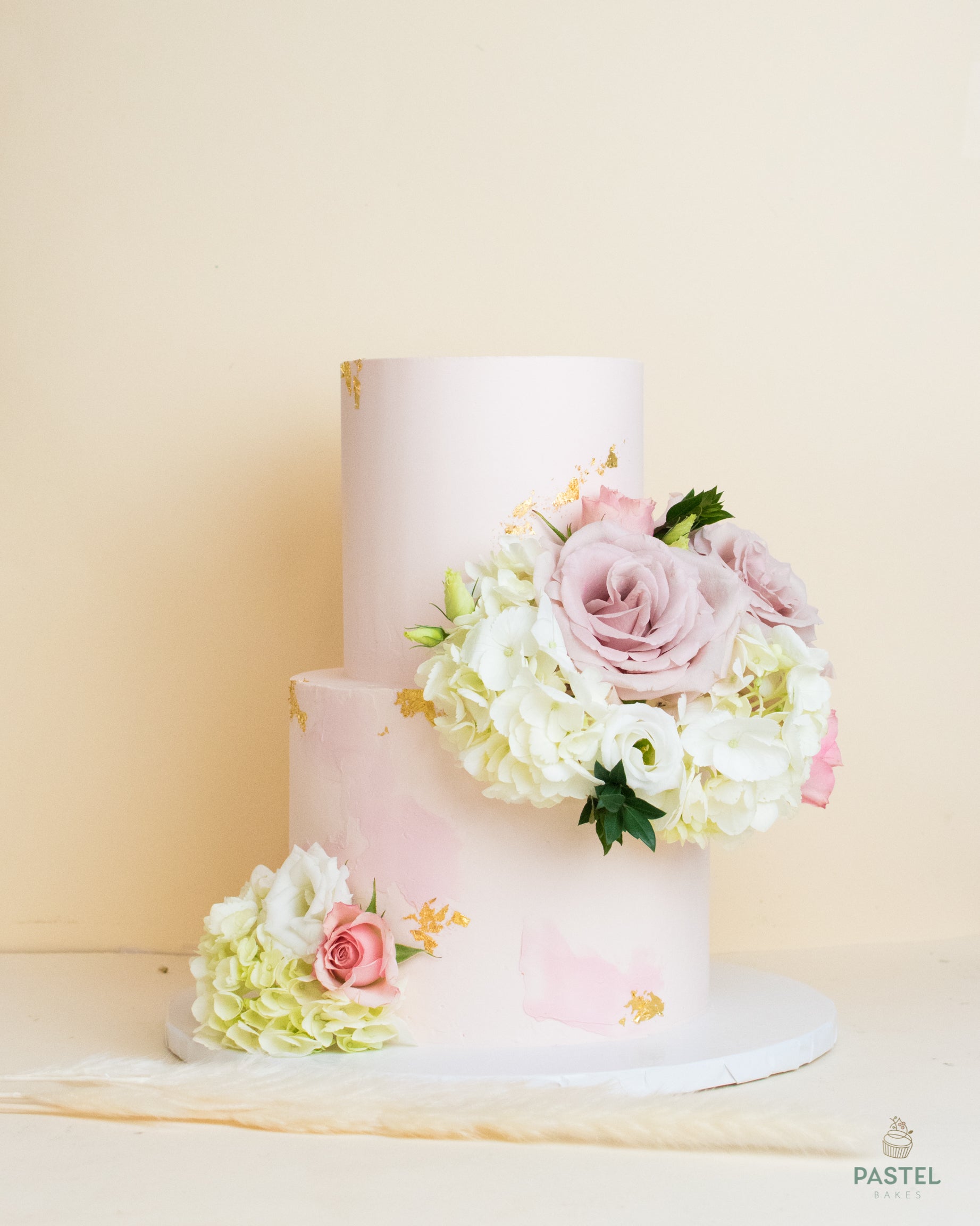 High two layers light-pink cake with decorative rose bouquet at the bottom and between layers.