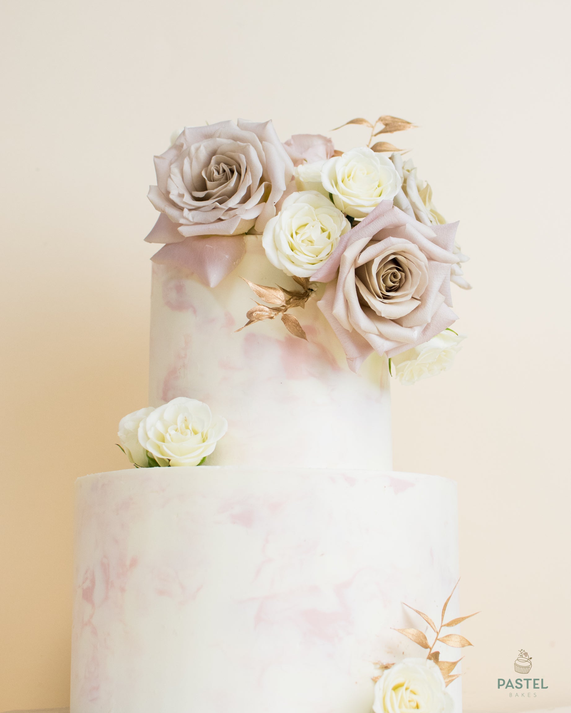 A high two-layer light-purple cake with a decorative rose bouquet at the top, two white roses between layers, and one white rose at the bottom.