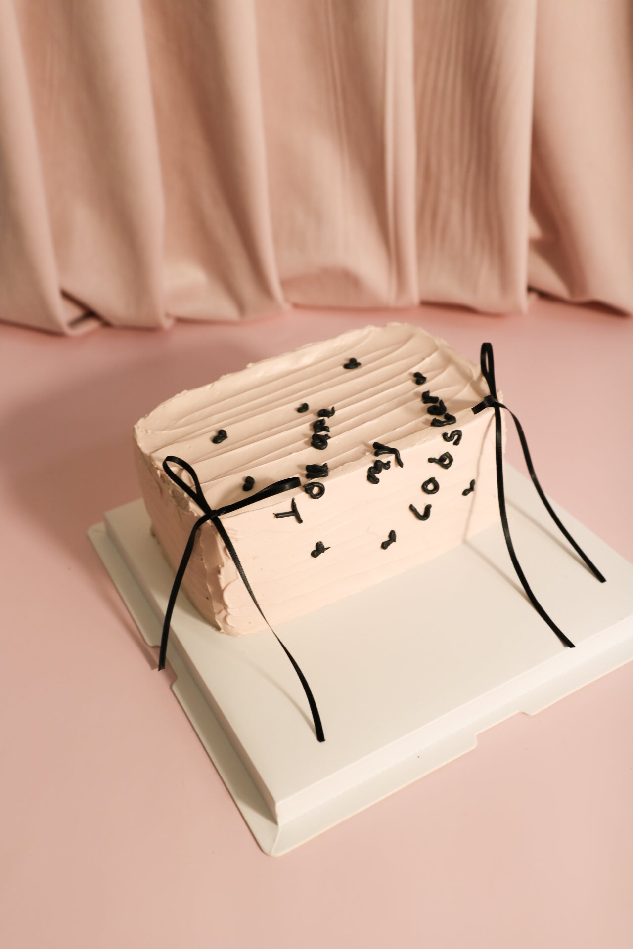 Light pink heartfelt message cake and two black ribbons