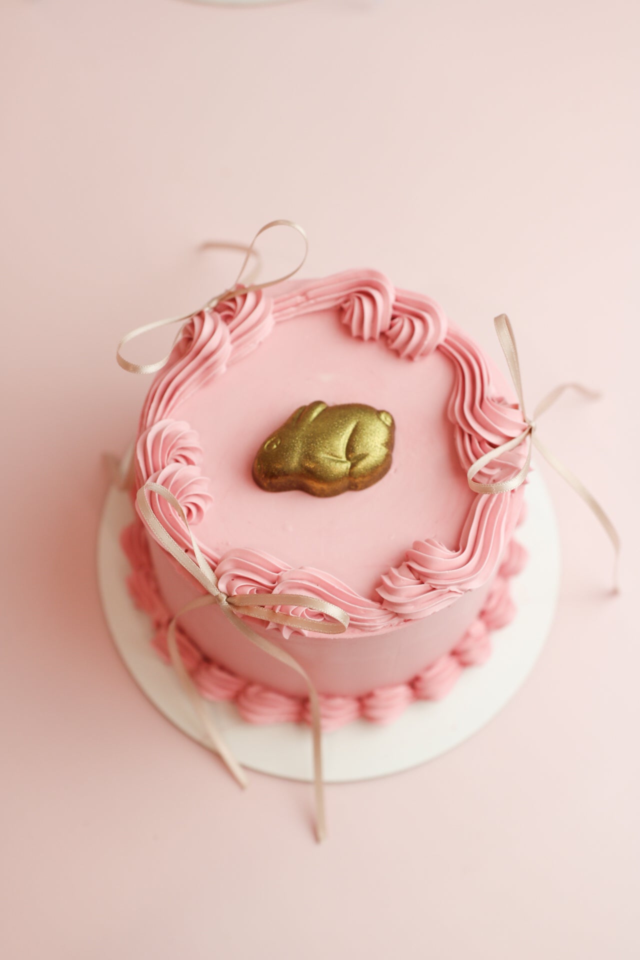 Rose easter cake with rose cream decor and a golden bunny on top of it