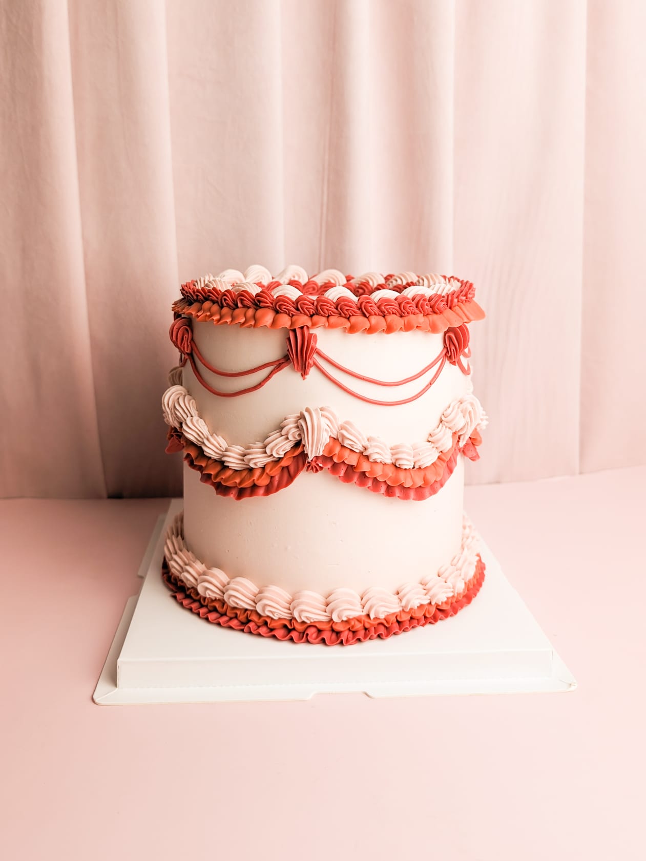Peachy Red Lambeth Cake with red and pink cream ruffles on top, middle, and bottom of the cake.